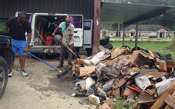 Men pile up debris outside a flooded auto parts store in Albany, La., Aug 17, 2016.