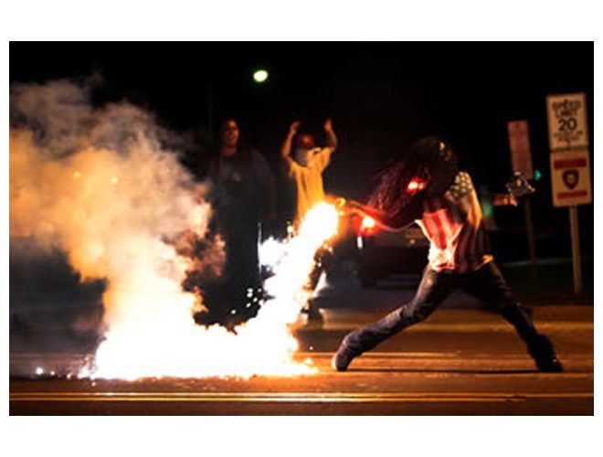 Protester throws back a tear gas canister that the police had fired at the people, Ferguson, August 13. Photo: AP
