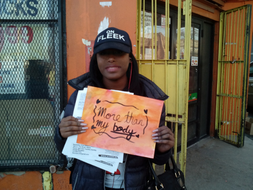 Young woman with "More than my body" sign