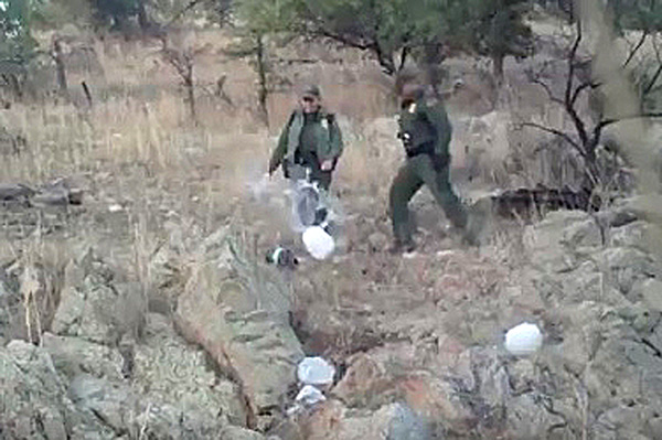 Agentes de la Patrulla Fronteriza patean contenedores plásticos de agua.