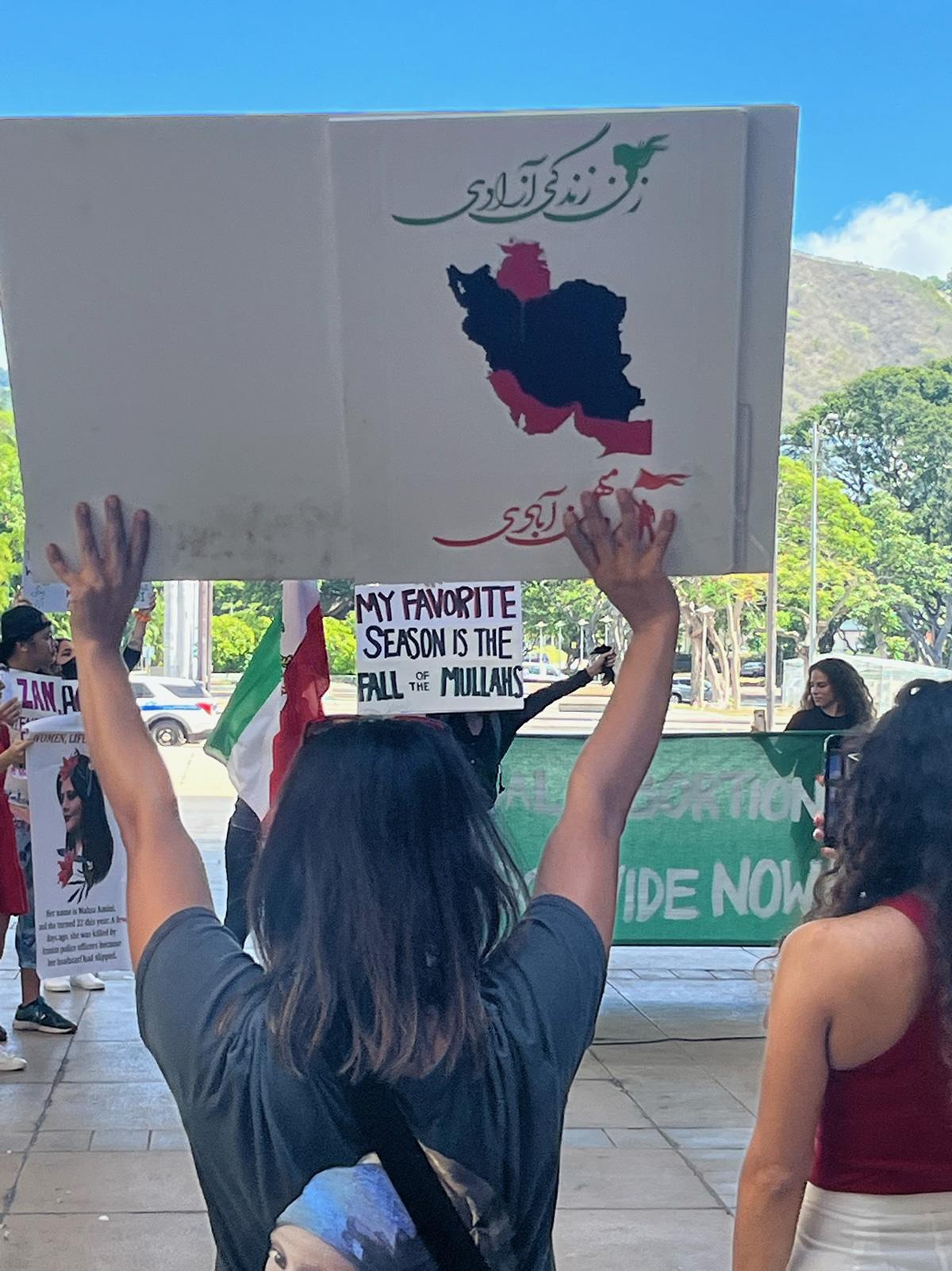 Woman holds sign "My favorite season is fall of mullahs" in Hawaii Women's March, October 8, 2022.