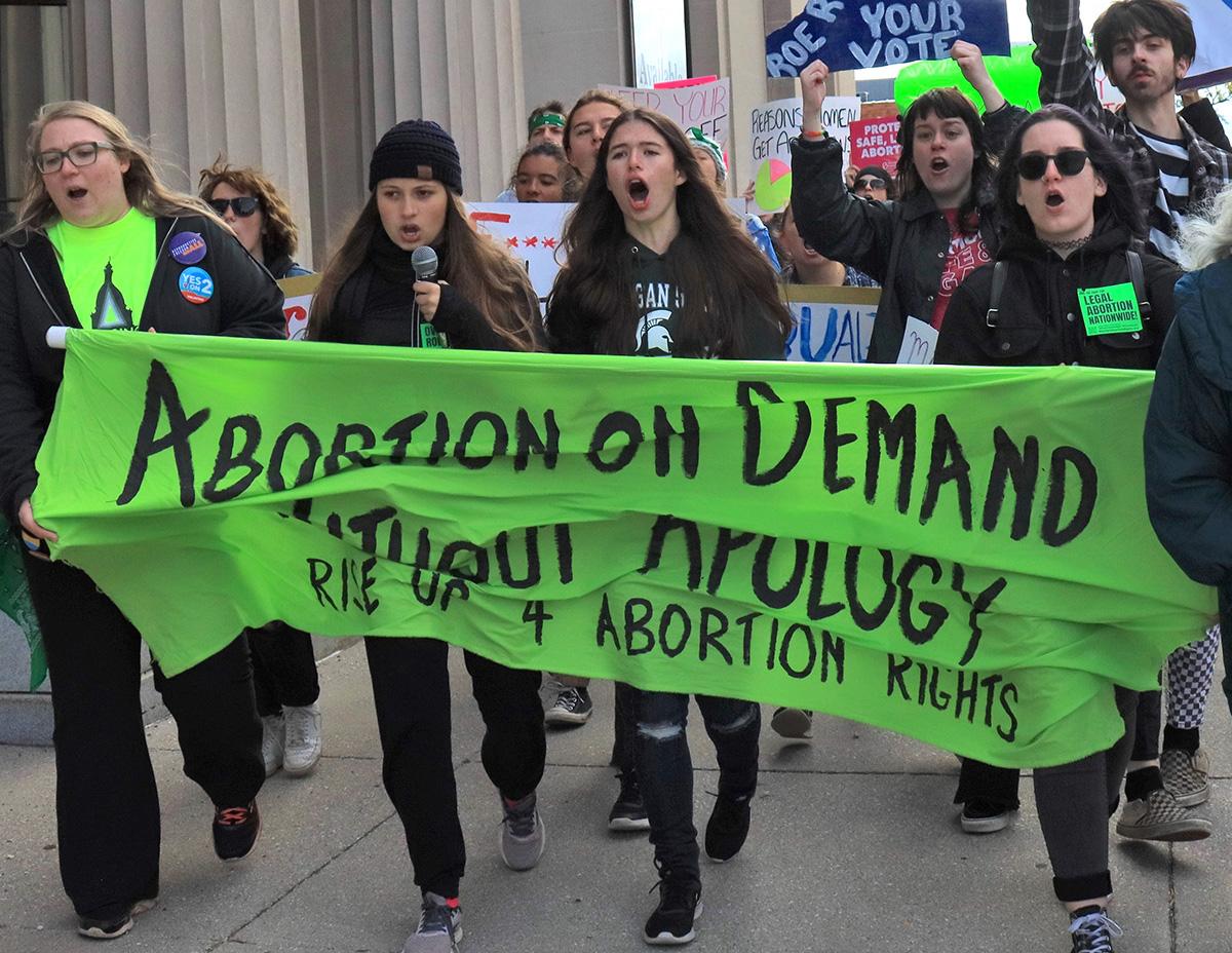 Lansing, Michigan, women march with banner, "Abortion on Demand Without Apology,", October 8, 2022
