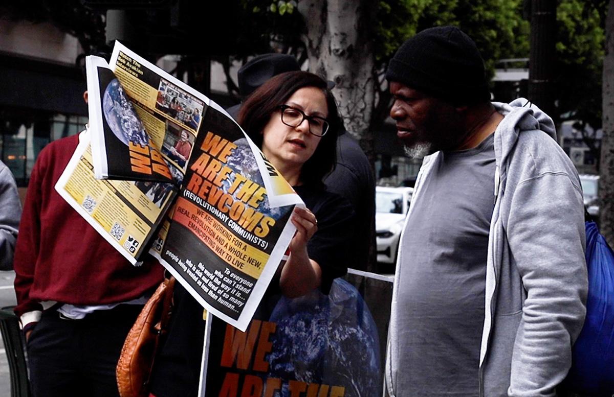 Los Angeles, May First, Sunsara Taylor shows broadsheet to guy.