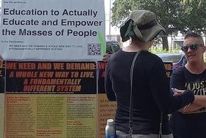 Two people discussing display including "Education to Actually Educate and Empower the Masses of People"