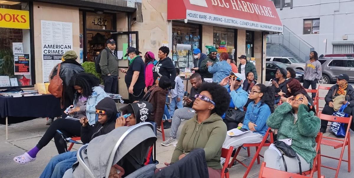Crowd of people outside Revolution Books NYC watching the eclipse