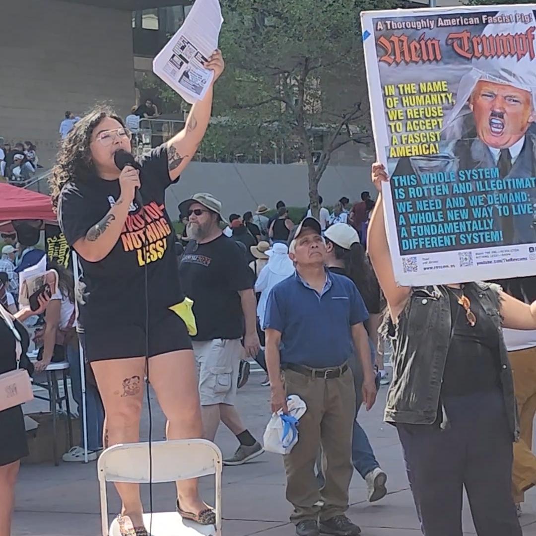 Revcoms standing on chair agitating to crowd at Bernie Sanders-AOC rally.
