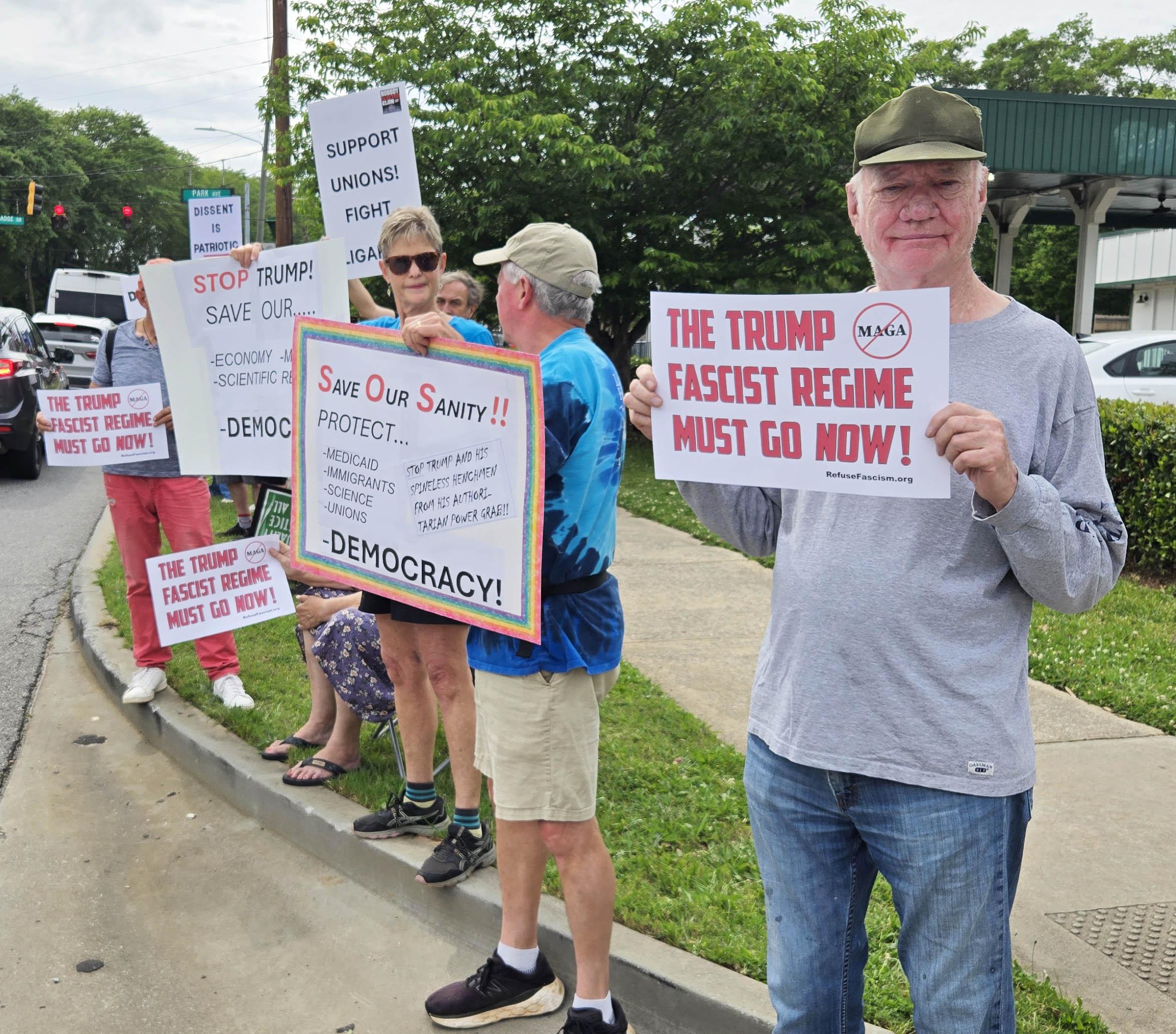 Athens, Georgia, residents hold signs by street, May Day 2025.