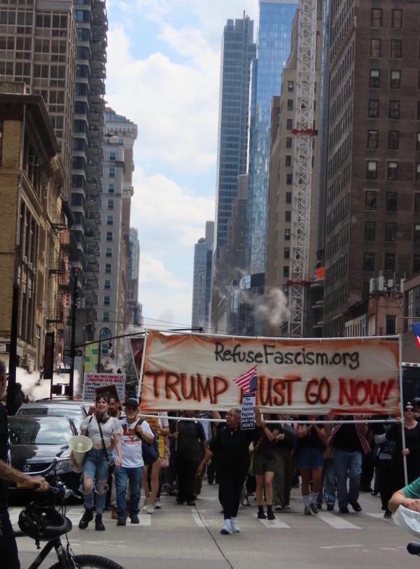 New York City refuse fascism marches behind Trump Must Go Now banner.