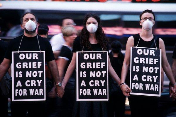 Three young women with signs our grief is not a cry for war.