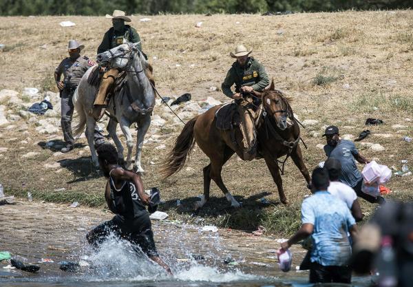 Mounted Texas Border Patrol on horseback whip and yell at Haitian immigrants who crossed the Rio Grande River from Mexico into the U.S. 