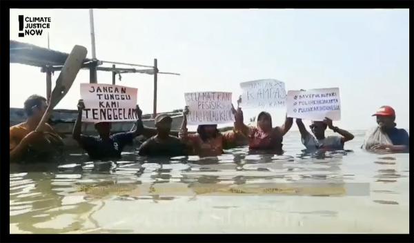 Indonesian protestors chest deep in water hold up signs, November 5, 2021