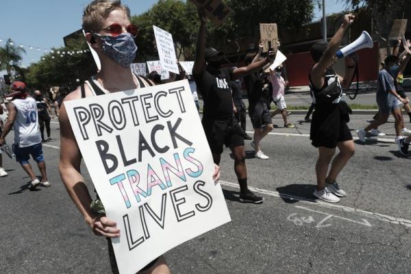 Woman with sign "Protect Black Trans Lives" in California IWD march.