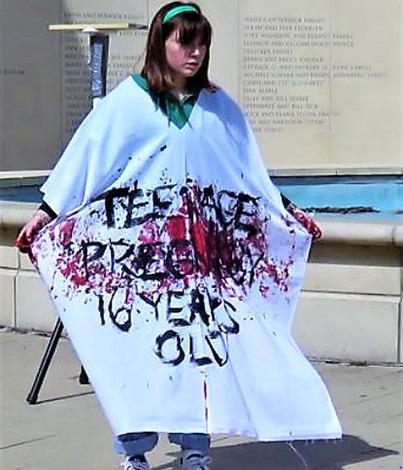 Woman with bloodied shirt that speaks of 16 year old who died from botched abortion.