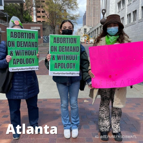 Three women hold signs for RiseUp4AbortionRights in Atlanta.
