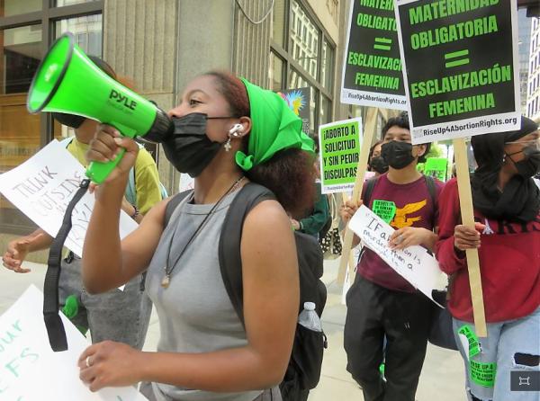 Student on bullhorn leads school walkout marching through Chicago Loop.