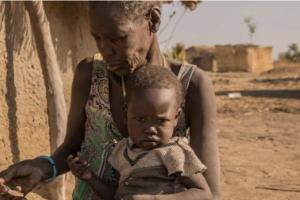 A mother giving sorghum porridge to her children. A growing number of children in South Sudan’s Northern Bahr el Ghazal and Warrap have only one meal per day.