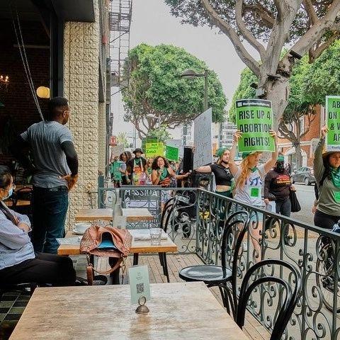 Santa Monica RU4AR protest marches past restaurants.