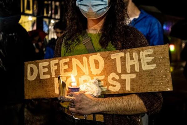 At candlelight vigil for activist Tortuguita, murdered by Georgia State Troopers , a sign: DEFEND THE FOREST.