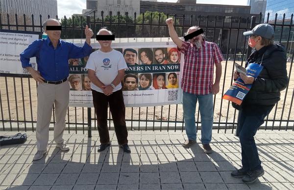 People stand in front of IEC banners to support Iran political prisoners, February 2023.