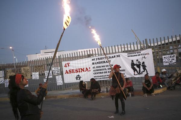 Mexico, Ciudad Juarez, protest fire that killed 39 migrants with signs on fence and torches, March 29, 2023.