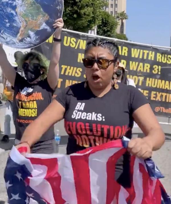 Woman with Revolution Nothing Less t-shirt tearing up U.S. flag