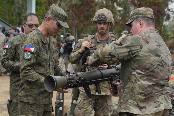 In joint military drills in the Philippines, a U.S. trooper demonstrates how t to Filipino soldier o use anti-tanker rifle, April 13, 2023.