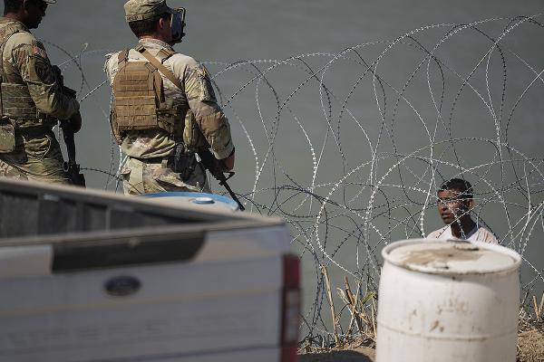 National Guardsmen confront a migrant who has just crossed the Rio Grande to the Texas border, July 2023.
