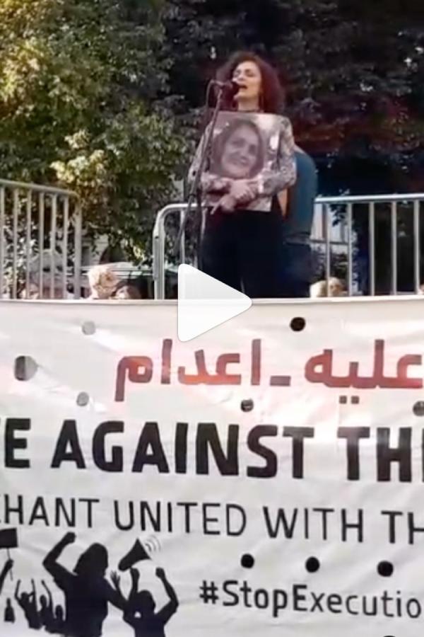 Iran ex-prisoner Somayeh Kargar speaking at Stop the Executions rally in Berlin, June 24, 2023, holding a photo of prisoner Nahid Taghavi.