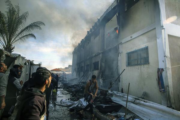 Palestinians try to extinguish a fire caused by Israeli strike at a building of an UNRWA vocational training center, January 24, 2024.