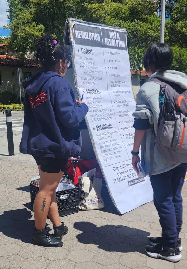 Revcom Corps sign on A-frame at student walkout, April 11, 2024.