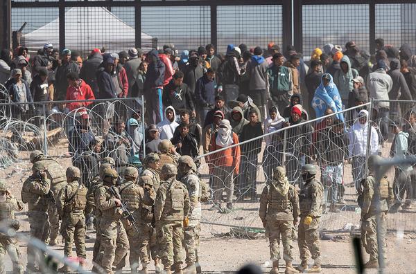 Texas National Guard corral migrants after they breached barriers set up on the Rio Grande in El Paso, Texas, March 21, 2024.