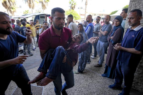 Man carries Palestinian child injured by  Israeli airstrike in Deir al Balah, Gaza Strip, October 10, 2024.