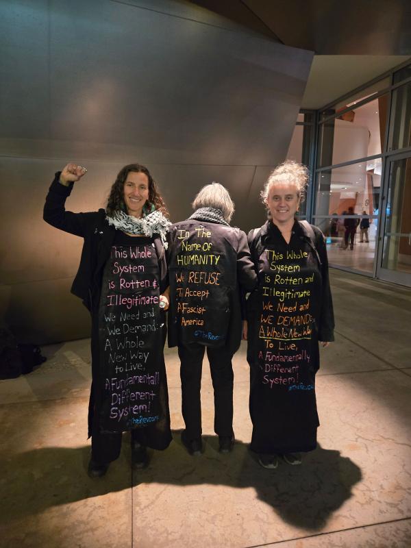 Three revcom women with elegant dresses printed with slogans. 