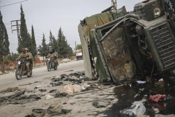 Syrian opposition fighters drive past a damaged government vehicle south of Hama, Syria, on Saturday, Dec. 7, 2024.