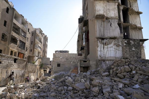Syrian children play next to a destroyed residential building in Aleppo, Syria, December 14, 2024. 