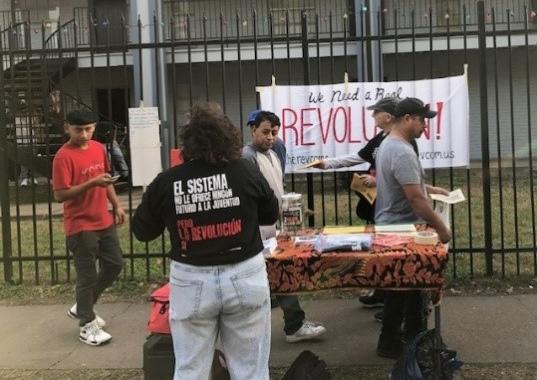 Revcom Corps at pulga in Houston. Banner reads "We Need a Real Revolution." 