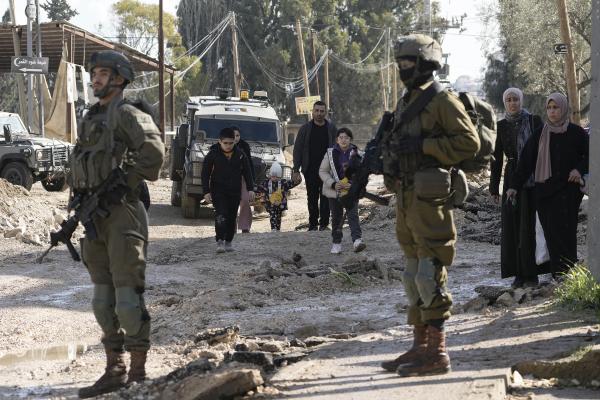 Israeli soldiers patrol as Palestinians displaced from the Jenin refugee camp in the West Bank carry their belongings, January 23, 2025.