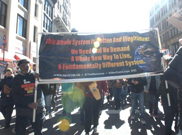 International Women's Day march in NYC. banner: This whole system is rotten and illegitimate. We need and we demand a whole new way to live, a fundamentally different system