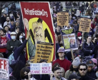 Refuse Fascism Hitler banner in middle of protest. "In the name of humanity, we refuse to accept a fascist America. 