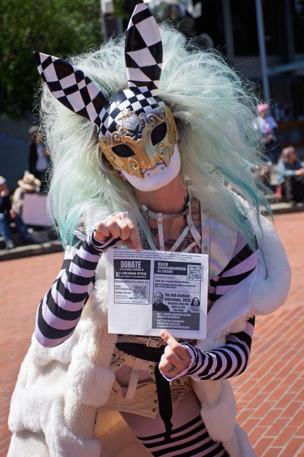 A protester dressed as a checkered bunny holding a leaflet from the revcoms.