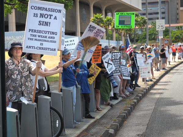 People line the streets of Honolulu with signs for Refuse Fascism rally, May 17, 2025.