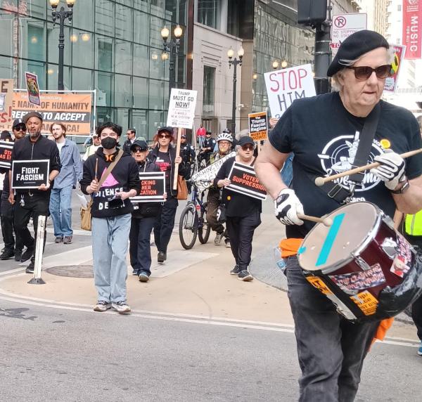 Drummer leads the Chicago march, followed by people with signs of fascist attacks, May 17, 2025.