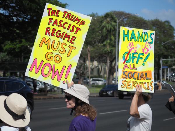 Women at Honolulu refuse fascism rally hold signs, The Trump Fascist Regime Must Go Now.