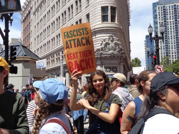 Marcher with sign "Fascist Attacks Beat Them Back" at No Kings Day rally in Oakland, June 14, 2025.