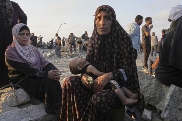 Starving Palestinian woman waits with her child for trucks with humanitarian aid to arrive in Gaza City, July 25, 2025.