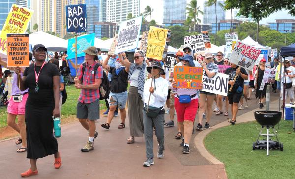 Honolulu, Hawaii, crowd marches with signs on July 4, 2025.