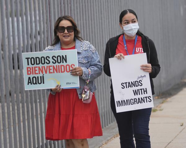 Teachers hold signs welcoming immigrant students on their first day of school in Los Angeles, August 14, 2025.