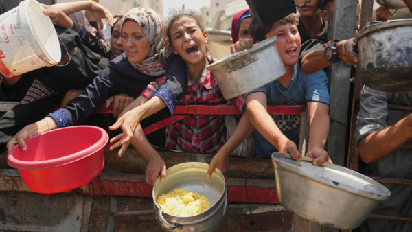 Palestinians struggle to get donated food at a community kitche in in Gaza City, August 16, 2025.