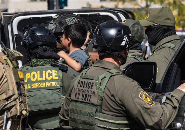 Federal agent carries a child during an imigration arrest in downtown Chicago, September 28.