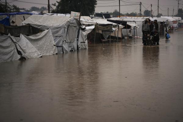 Palestinians cross street flooded by storm Byron in Khan Younis, December 11, 2025.
